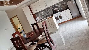 A modern kitchen with white cabinets, a black tiled backsplash, and a stainless steel refrigerator.