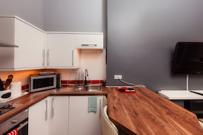 Enjoy cooking in this fully equipped kitchen with a microwave, sink, and mounted TV.