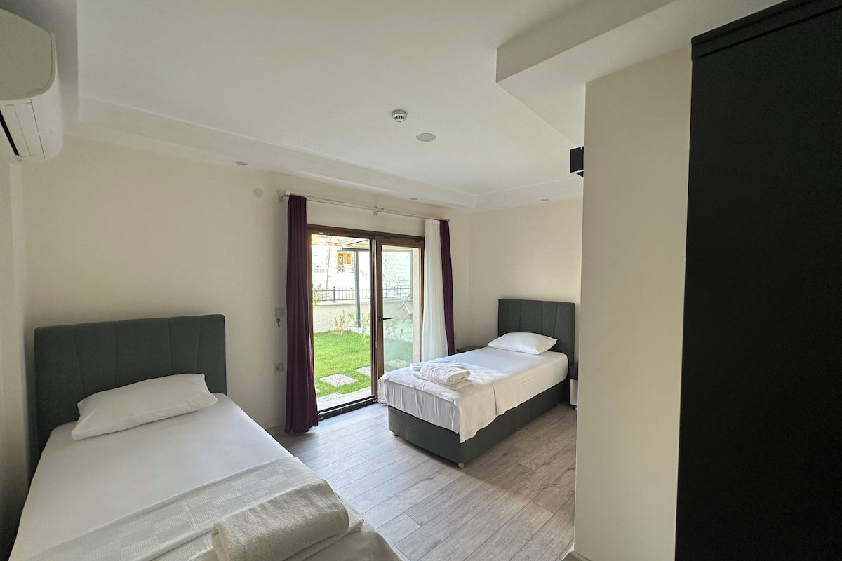 A hotel room with two beds, a sliding glass door to the outside, and a modern design.