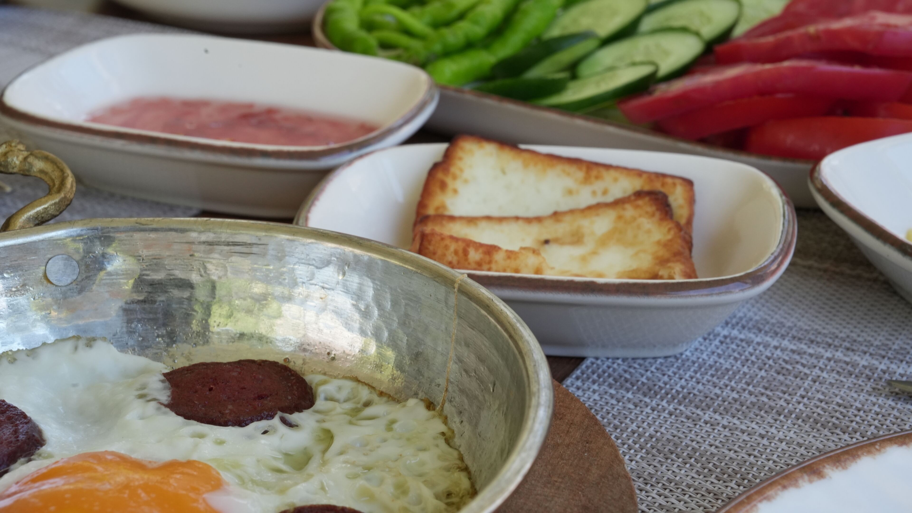 A breakfast setting with various dishes including eggs, sausage, toast, and vegetables.