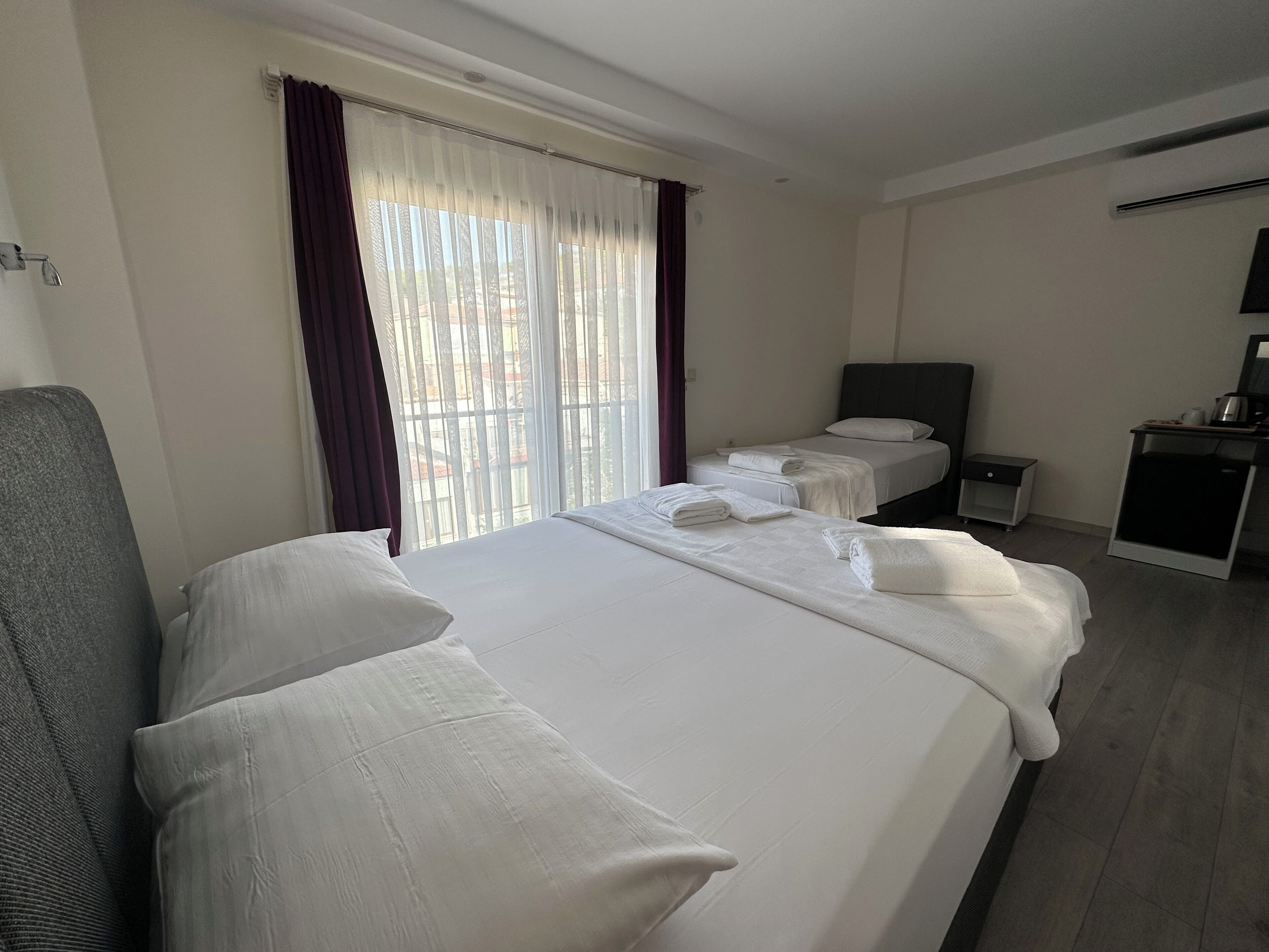 Une chambre d’hôtel avec un grand lit, deux petits lits, un bureau et une chaise.