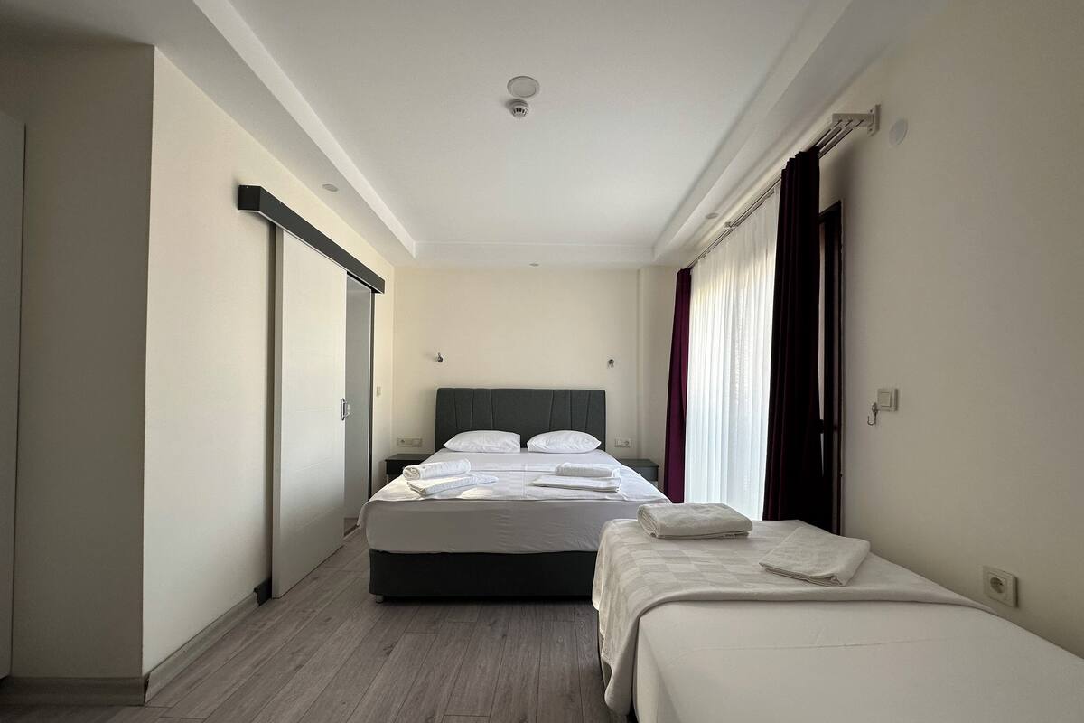 A hotel room with a large bed, a smaller bed, a wardrobe, and a bathroom.