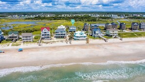 Une station balnéaire dotée de propriétés situées en bord de mer, notamment des maisons avec balcon et une plage aménagée avec des parasols.