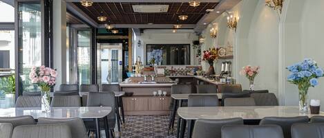 Un restaurante moderno con una isla central, varias zonas de estar e iluminación decorativa.