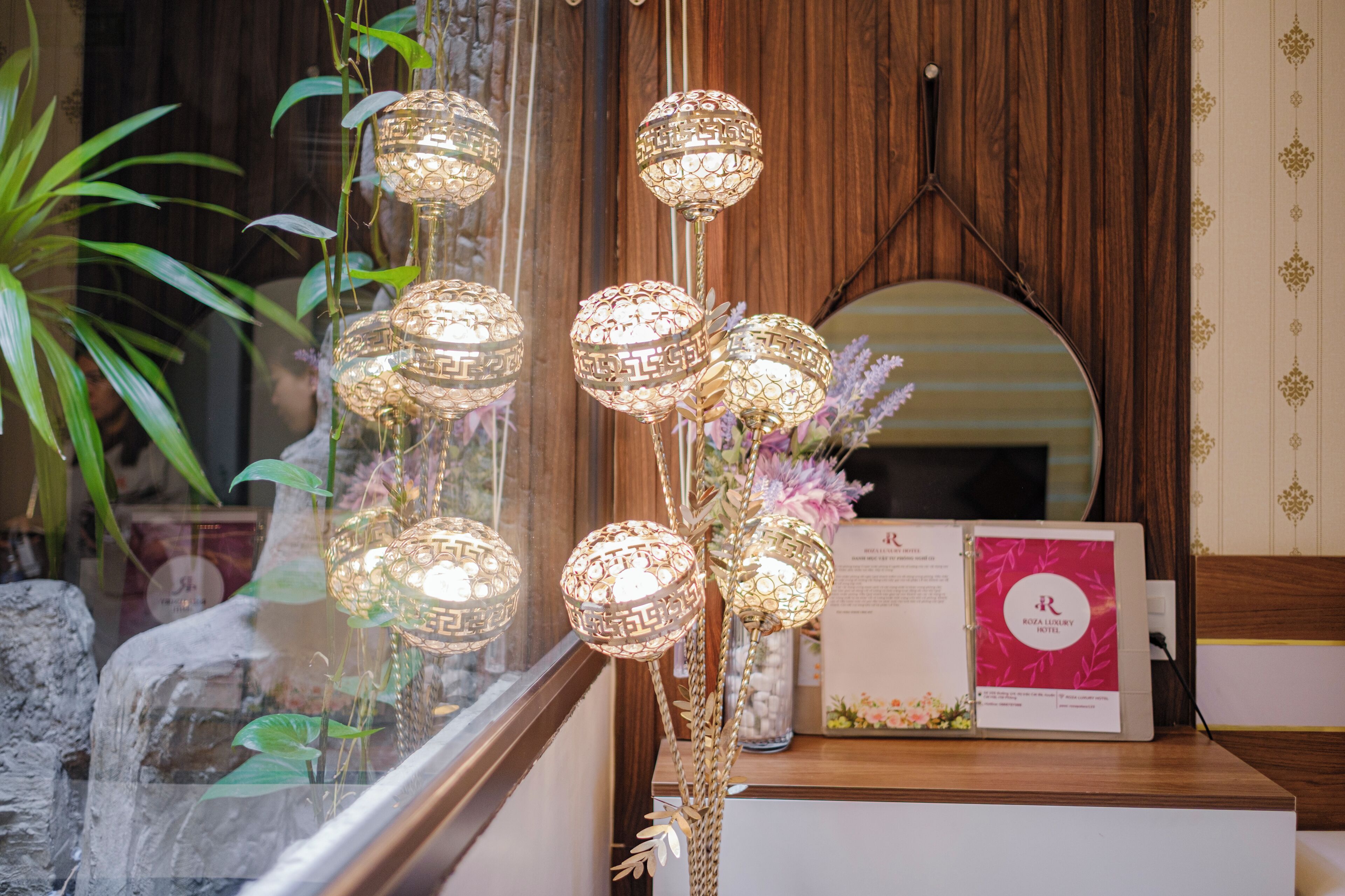 Een receptiebalie met een houten achtergrond, een spiegel en een decoratieve lamp.
