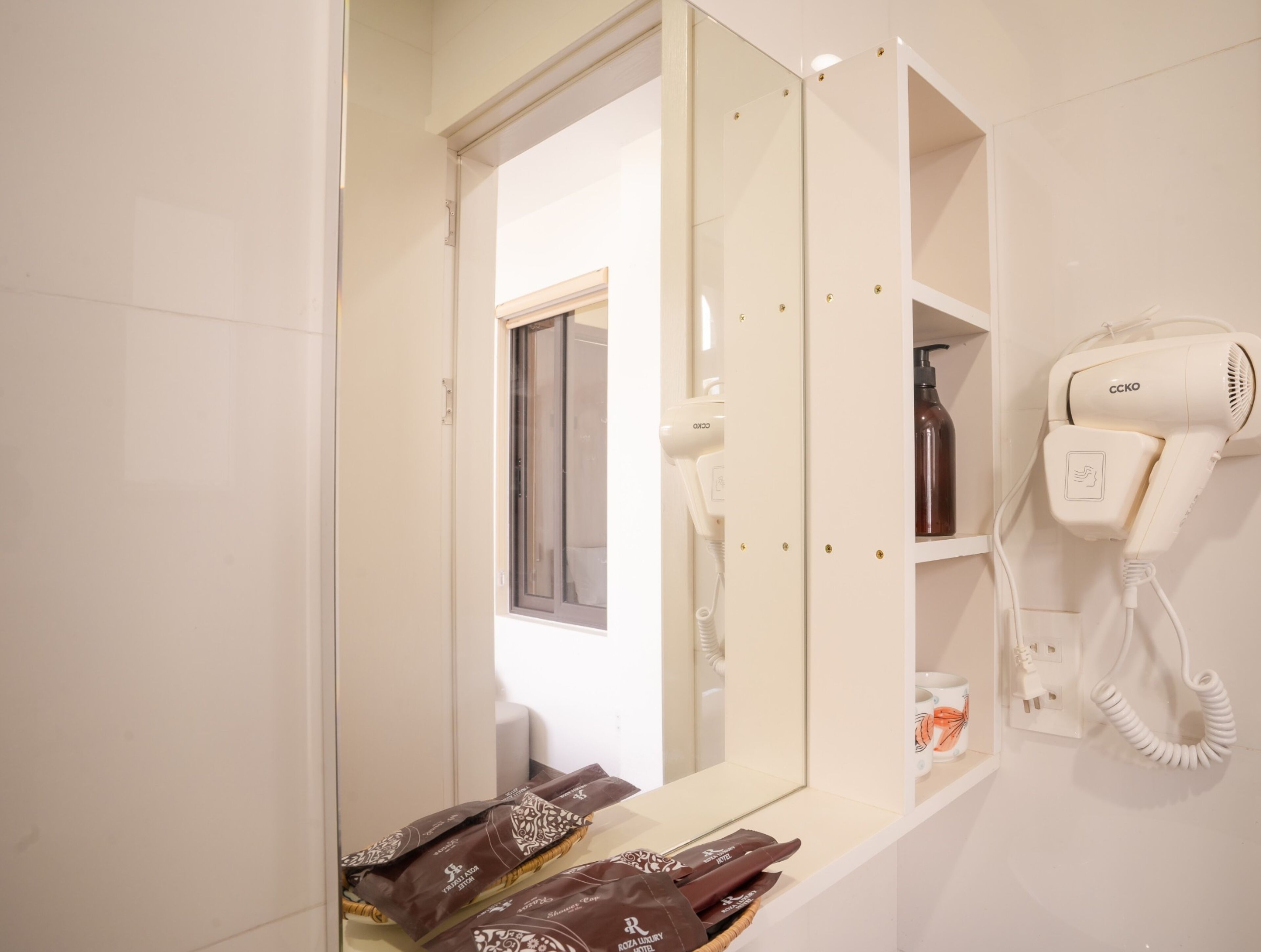 Een badkamer met een haardroger, een spiegel en een plank met toiletartikelen.