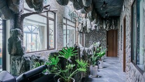 A hallway with a stone wall, potted plants, and a wooden door. - Roza Palace (Hai Phong)