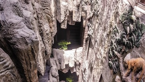 A rock garden with a small pond, a climbing wall, and a window with a view. - Roza Palace (Hai Phong)