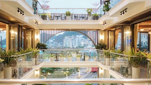 A multi-level atrium with glass railings, potted plants, and seating areas. - Roza Palace (Hai Phong)