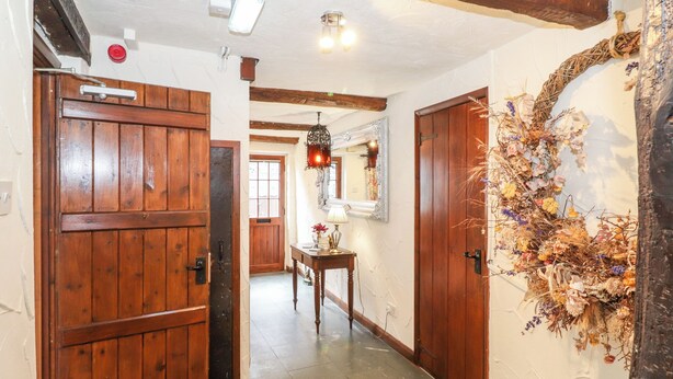 Un corridoio con porte in legno, uno specchio e un'ampia composizione floreale appesa al muro.