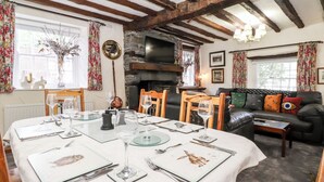 Zona pranzo con un tavolo rotondo apparecchiato per quattro persone, sedie di legno e un camino in pietra.