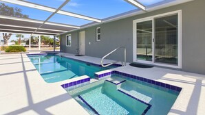 A swimming pool with a glass enclosure, a covered patio area, and a sliding glass door leading to a covered outdoor space. - Spoonbill Lagoon with Fantastic Water Views of Palma Sola Bay! (Bradenton)