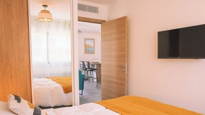 A hotel room with a bed, a television, and a door leading to a dining area. - New 4 bedroom house, superb view of Calvi bay (Calvi)