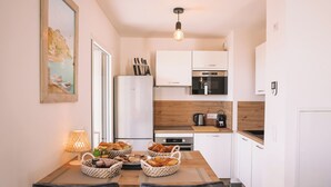 A modern kitchen with white cabinets, a Bosch refrigerator, a coffee machine, and a wooden countertop. - New 4 bedroom house, superb view of Calvi bay (Calvi)