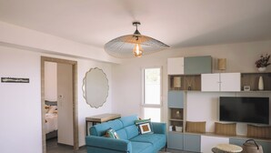 A modern living room with a teal sofa, a large mirror, a television, and built-in shelving. - New 4 bedroom house, superb view of Calvi bay (Calvi)