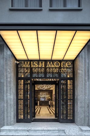 The entrance of the Wishmoe Hotel with a modern design, featuring a large illuminated sign above the entrance and a geometric patterned glass door. - Wish More Hotel Şişli (Istanbul)