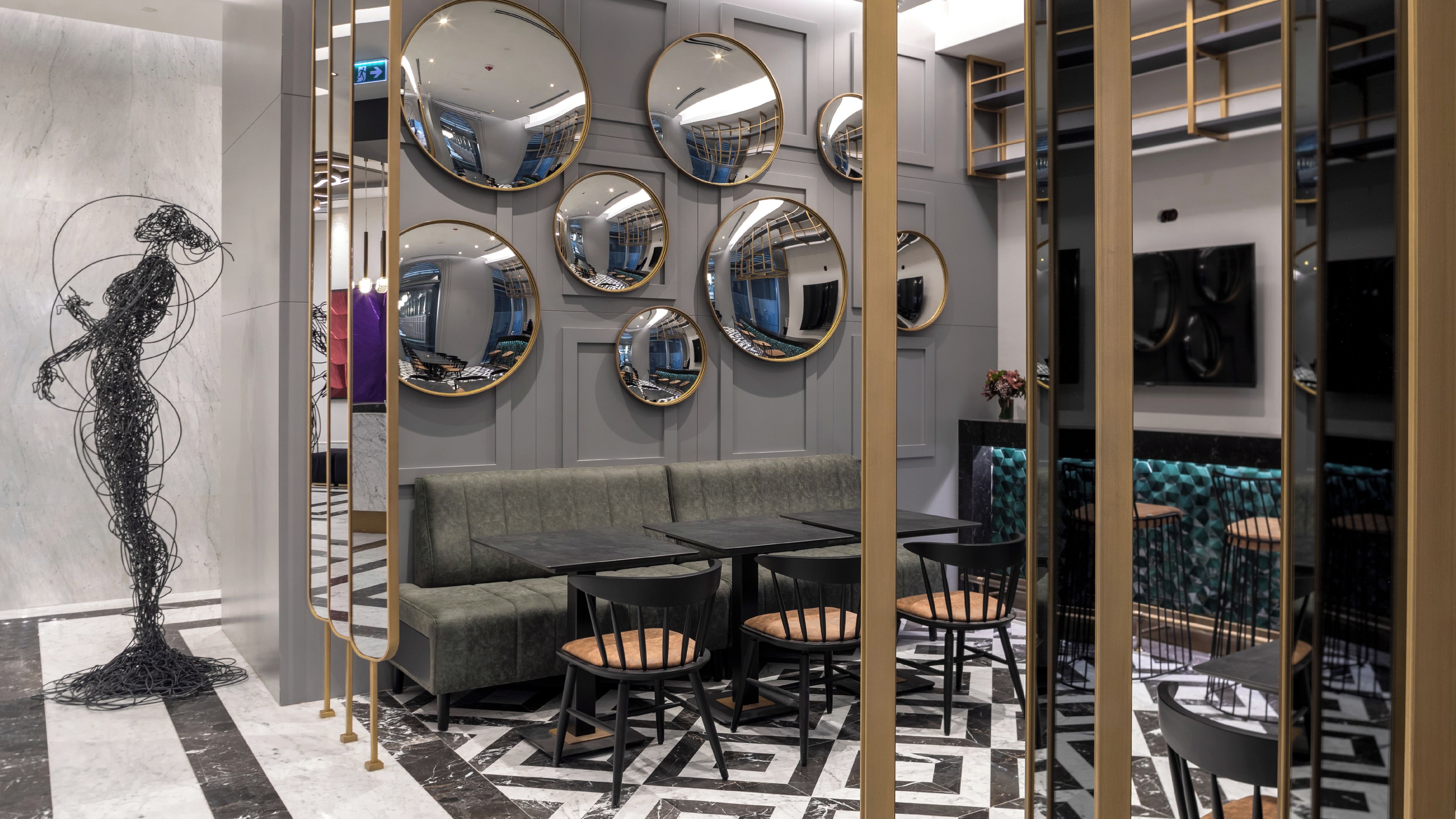 A modern interior with a sofa, tables, chairs, and multiple mirrors on the wall.