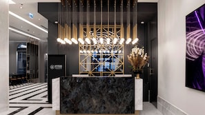 A reception area with a marble counter, a modern chandelier, and a decorative wall with a geometric pattern.
