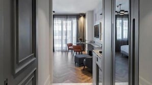 A hallway leading to a bedroom with a large window, a desk with a chair, and a television. - Wish More Hotel Şişli (Istanbul)