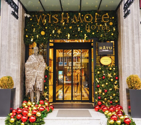The entrance of the Wishmore Hotel with a large statue, Christmas decorations, and a sign indicating it's in Istanbul.