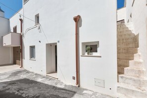 A narrow street with white buildings, a visible window, and a staircase. - 3601 La Corte di Alice by Barbarhouse (Casarano)