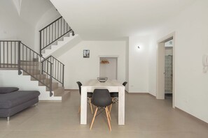 A modern living room with a dining table, black chairs, a grey sofa, and a staircase. - 3601 La Corte di Alice by Barbarhouse (Casarano)