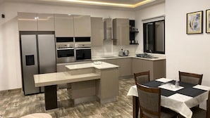 A modern kitchen with a central island, built-in appliances, and a dining area with a table and chairs. - 24 Roma (Lusaka)