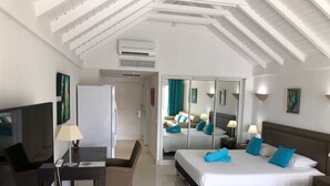 A hotel room with a bed, a desk with a chair, a TV, and a minibar.