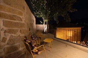 An outdoor seating area with stone walls, a wooden table, and chairs.