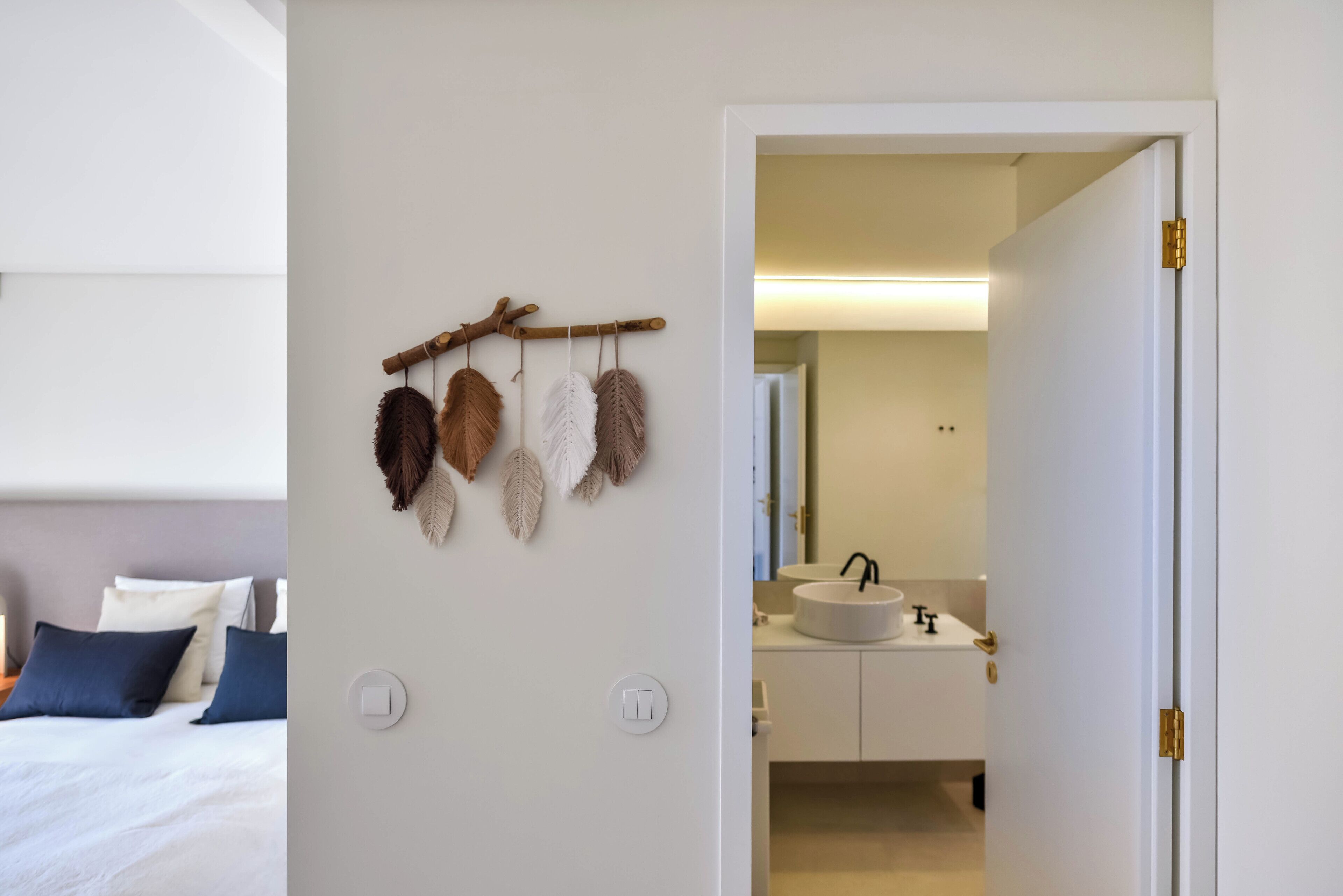 Une chambre à coucher avec un lit, un interrupteur fixé au mur et une branche décorative ornée de feuilles.