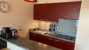 Een moderne keuken met rode kastjes, een roestvrijstalen spoelbak en een koffiezetapparaat.