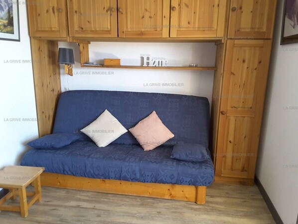Un canapé bleu avec des coussins, des meubles en bois et une petite table dans une pièce.