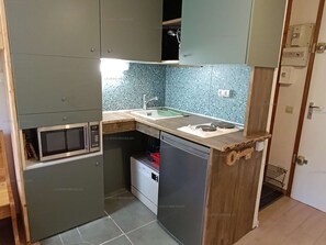 Una cocina compacta equipada con microondas, fregadero y lavavajillas.
