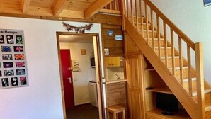 Un interior de madera con una escalera, una pequeña cocina y una mesa de comedor.