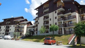 Un edificio residencial de varios pisos con balcones, un estacionamiento y una escalera que conduce a la entrada.