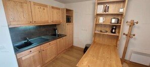 Eine kleine Küche mit Holzschränken, einer Spüle und einer Mikrowelle.