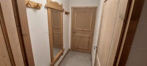 Un couloir étroit avec des portes en bois et un banc en bois.