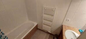 Ein Badezimmer mit einer Badewanne, einem weißen Handtuchhalter, einer Toilette und einem Waschbecken.
