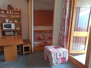 A compact room with a wooden table, a microwave, a bench, and a small stool. - Paradiski closed to the slopes vallandry (LANDRY)