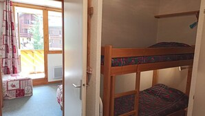 A bunk bed with patterned bedding, a window with curtains, and a view of buildings outside. - Paradiski closed to the slopes vallandry (LANDRY)