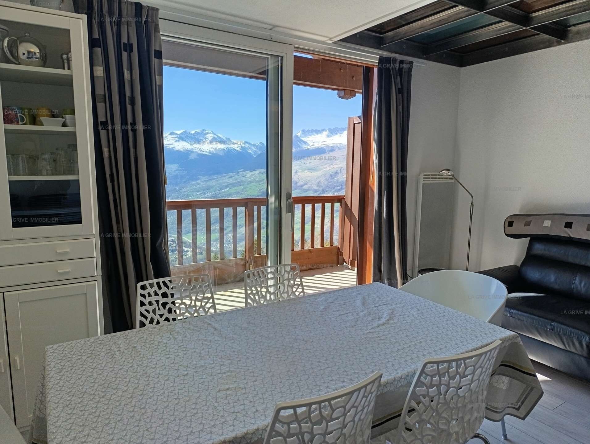 Una habitación con una mesa de comedor, sillas, un sofá y vistas a montañas nevadas a través de un ventanal corredero.