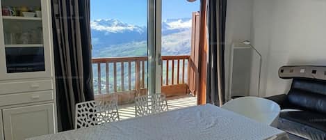 Una habitación con una mesa de comedor, sillas, un sofá y vistas a montañas nevadas a través de un ventanal corredero.
