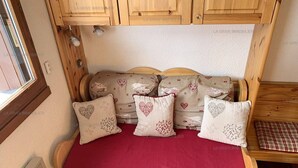 Un lit confortable avec une couverture rouge, une tête de lit en bois et des oreillers à motifs en forme de cœur.