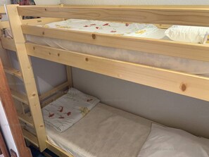 Un lit superposé à deux niveaux, chaque niveau étant équipé d’un oreiller et d’une couverture à motifs floraux.