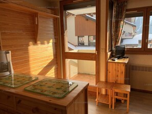 Un intérieur en bois comprenant un coin cuisine, une table à manger et un téléviseur posé sur un meuble en bois.