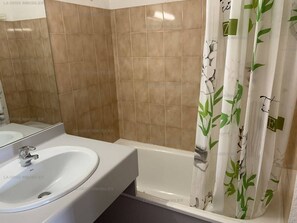 A bathroom with a white sink, a mirror, and a shower curtain with a green leaf pattern.