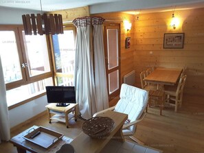 Una habitación acogedora con televisión, una mesa de comedor y una ventana con cortinas.