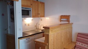 Une cuisine compacte avec des meubles en bois, un four à micro-ondes, un évier et un banc en bois.