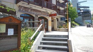 A building with a sign for 'Le Refuge Pizza' and a staircase leading to the entrance.