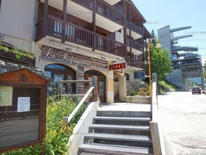 Un edificio con un letrero que dice 'Le Refuge Pizza' y una escalera que lleva a la entrada.